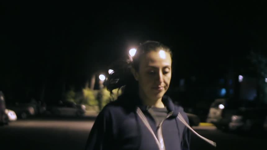 Woman running down a street in the dark