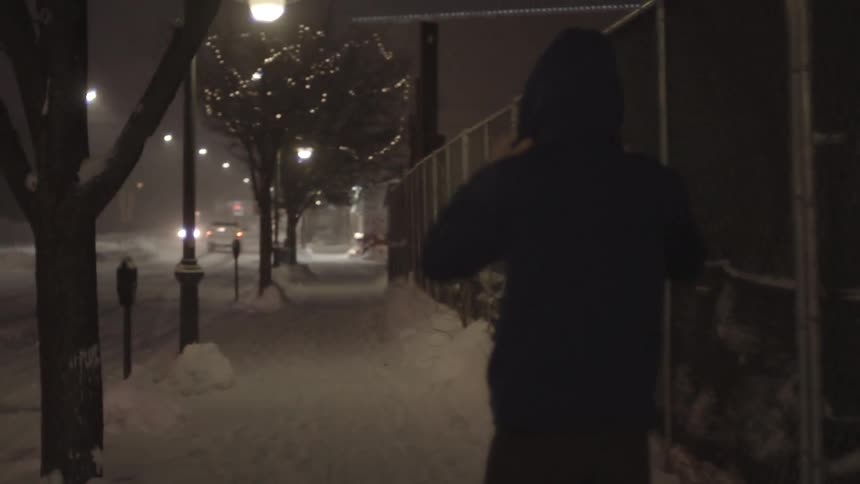A man walks down a snowy city sidewalk