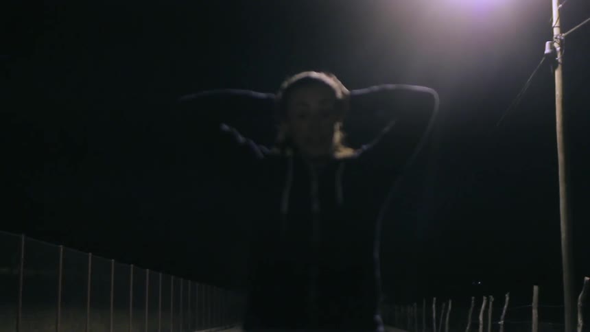 Woman stretching on a track in the dark