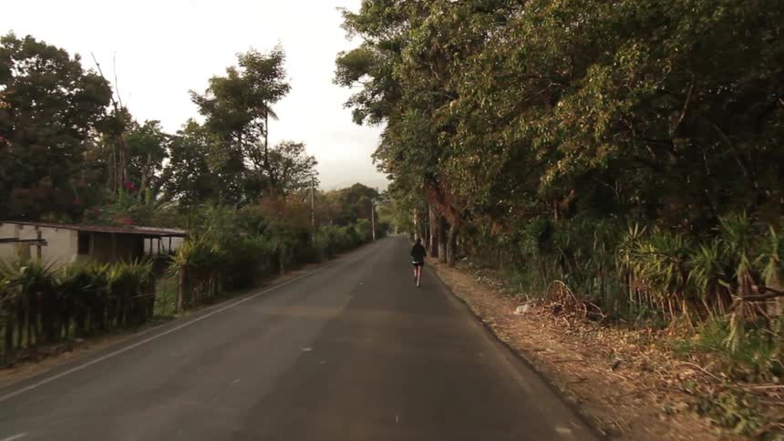 A person jogs down a vegetated road
