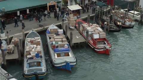 People walk past boats at a dock