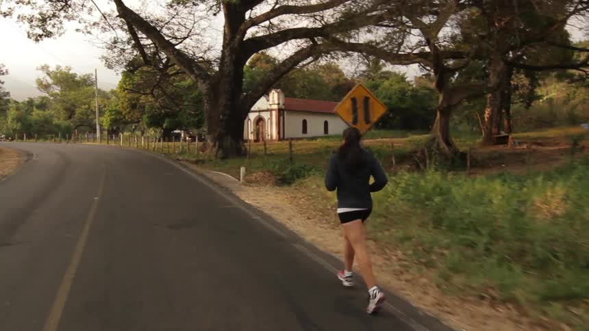Woman jogging down a road on a cloudy day