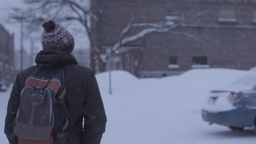 A man walks down a city street during a snowstorm