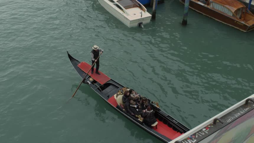 A man rows a boat full of people down a canal