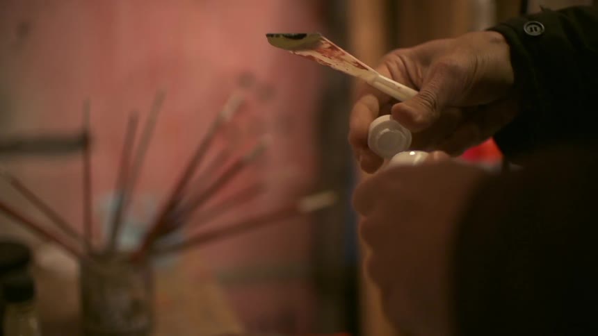 A man unscrewing the lid off paint