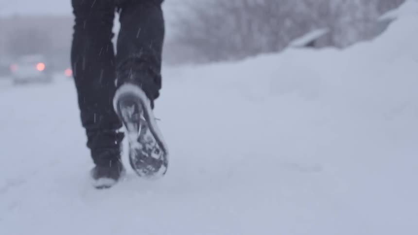 A person walks down a city sidewalk during a winter storm