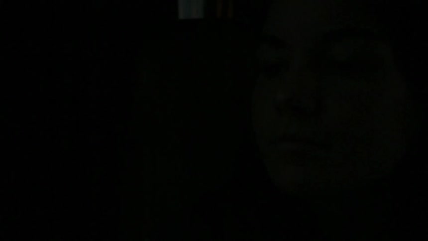 Light flashes on and off a woman's face as she looks down