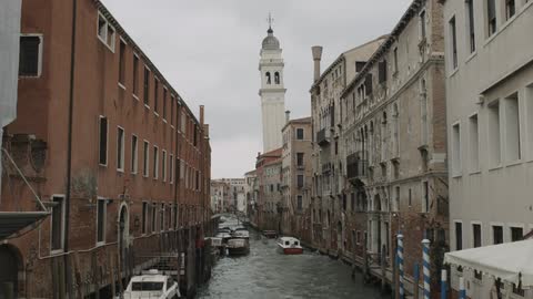 A boat travelling down a narrow canal between buildings