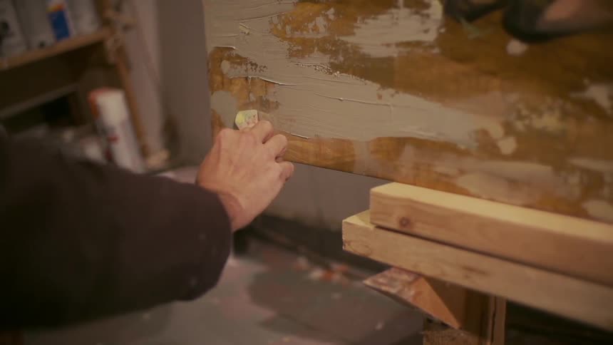 Man painting the edge of a canvas