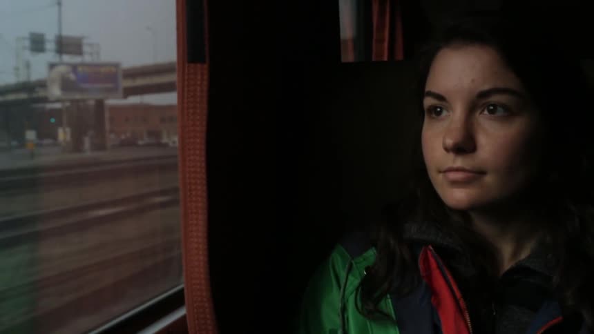 A girl sits on a train and gazes out the window