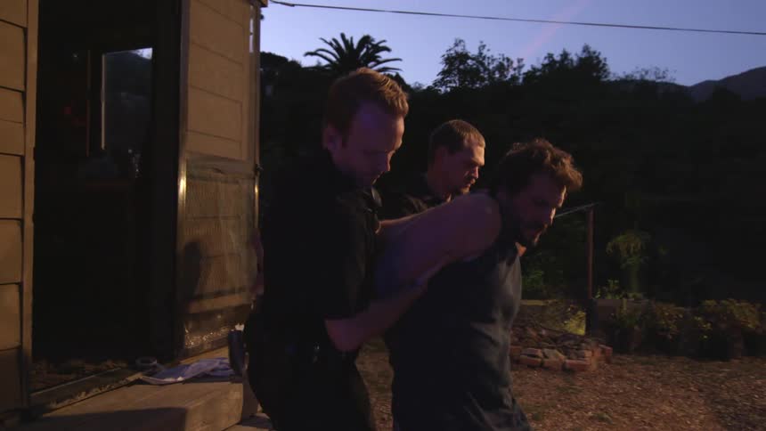 Police removing a man from a home at sunset