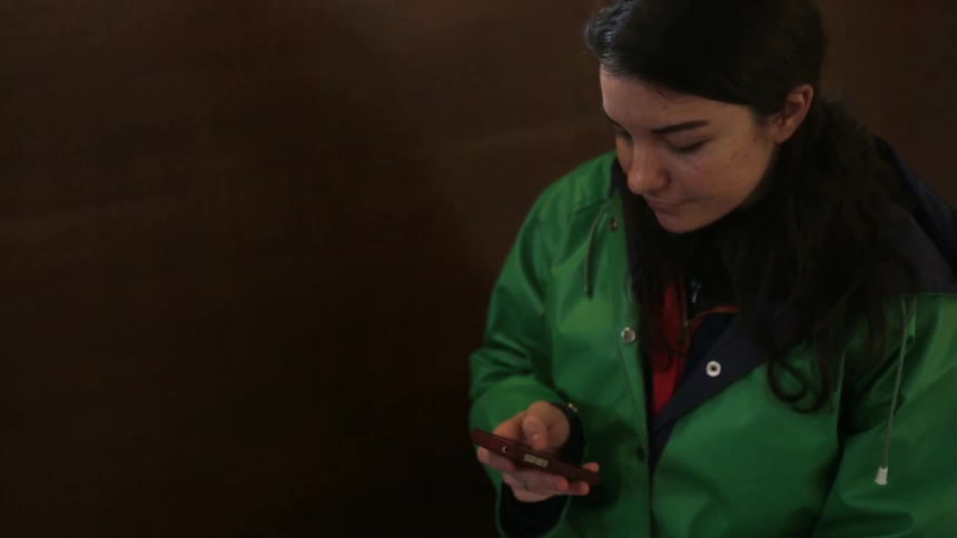 A young woman looking at her phone, touching the screen and smiling