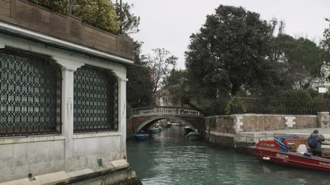 People crossing a foot bridge that spans a canal located in an urban area