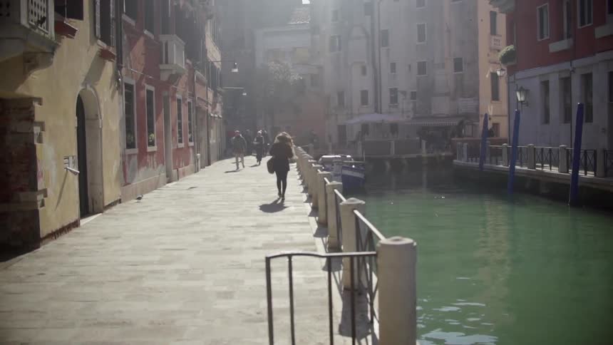 People walking beside a canal in a busy town