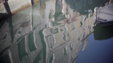 Buildings reflecting in water next to a docked boat