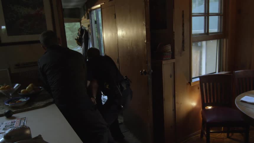 Man being detained inside of a dark home