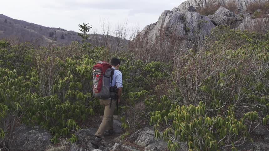 Man hiking up to a rocky hill on a cloudy day
