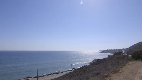 Cars drive along a beachfront road