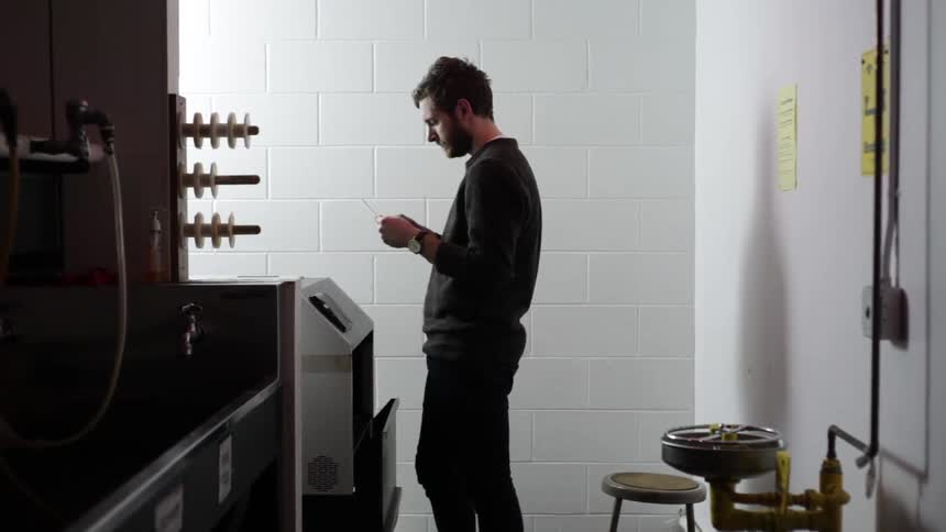 A white man waits in a room for a machine to kick out a piece of paper