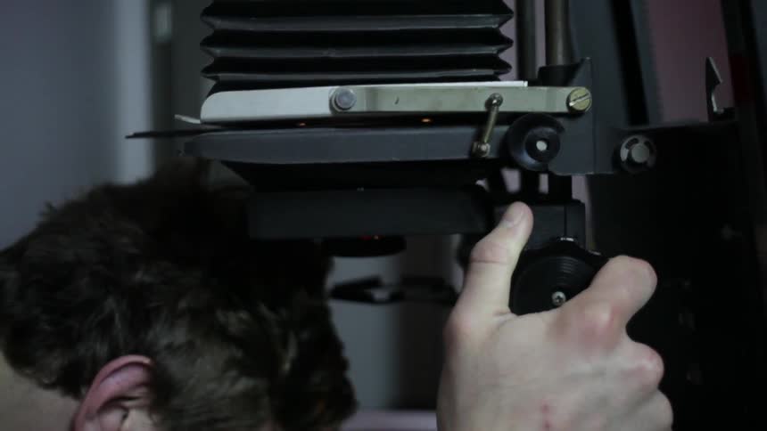 A man adjusts a microscope with a knob