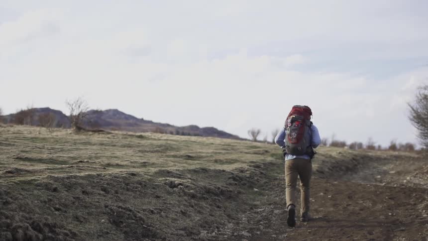 A person walks down the road wearing a backpack