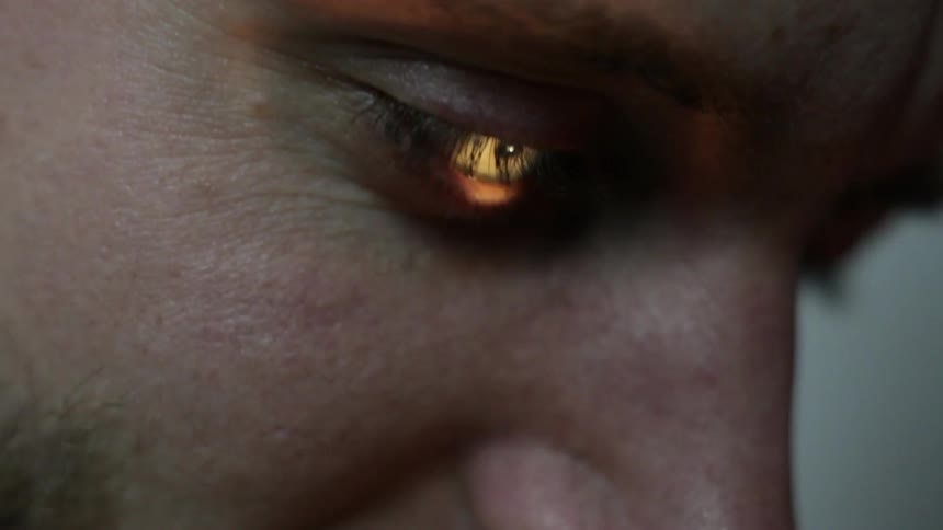 Man examining something as a light hits his eye