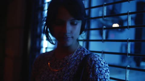 Woman standing in front of a window in a flowered dress with a blue hue all over