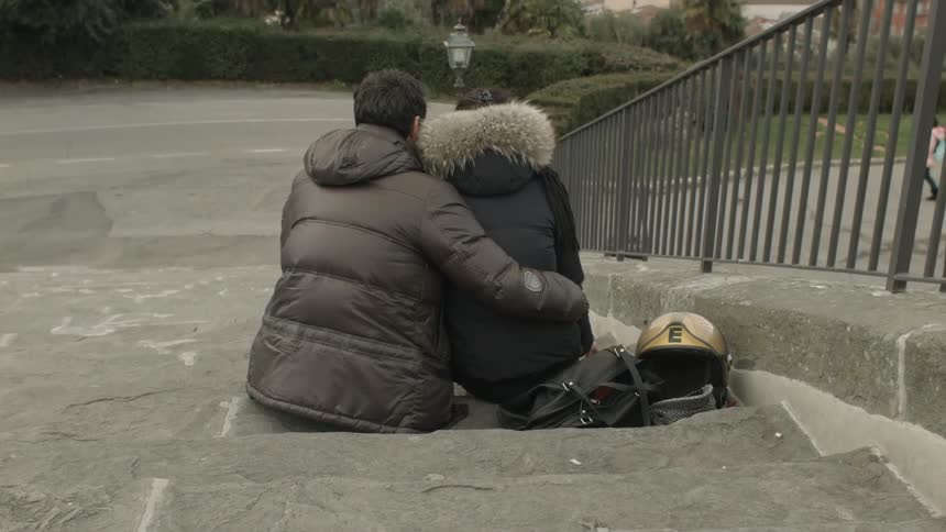 Man holding a woman as they sit on stone steps