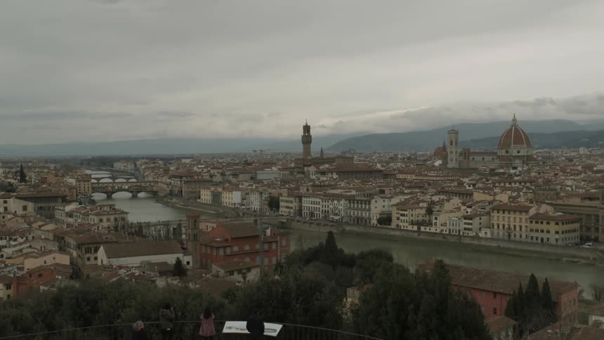 Wide shot of an old european city on a river with people looking out at the view