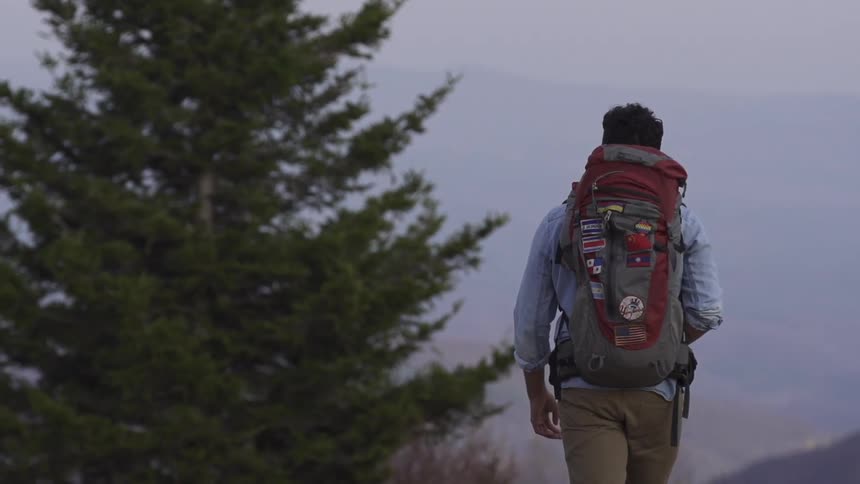 A man hikes on some hills on a cloudy day