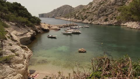 Many small boats in a lagoon and a man lying on a tiny section of beach