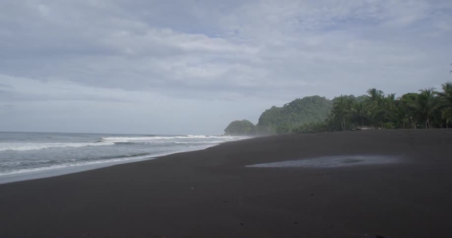 The view pans over a deserted beach and ends where the ocean waves are rolling in