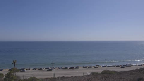 Cars drive past a beach on a sunny day