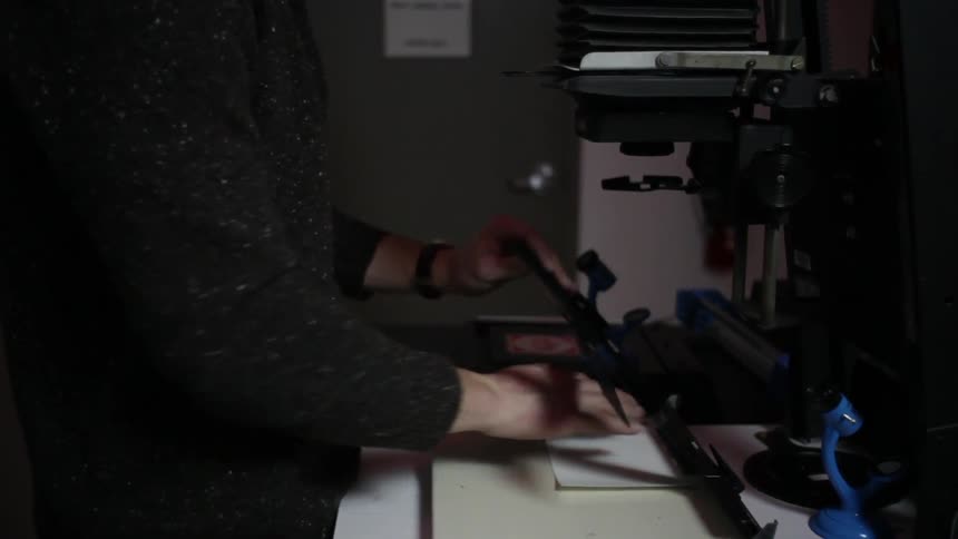 Photographer frames photography paper under a vintage camera inside a studio