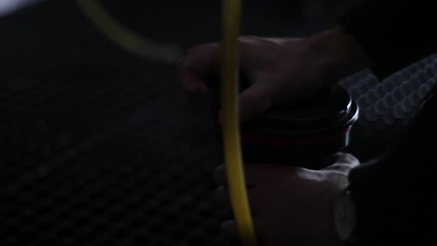 A man tipping a canister back and forth before unscrewing the lid from it and pouring liquid out