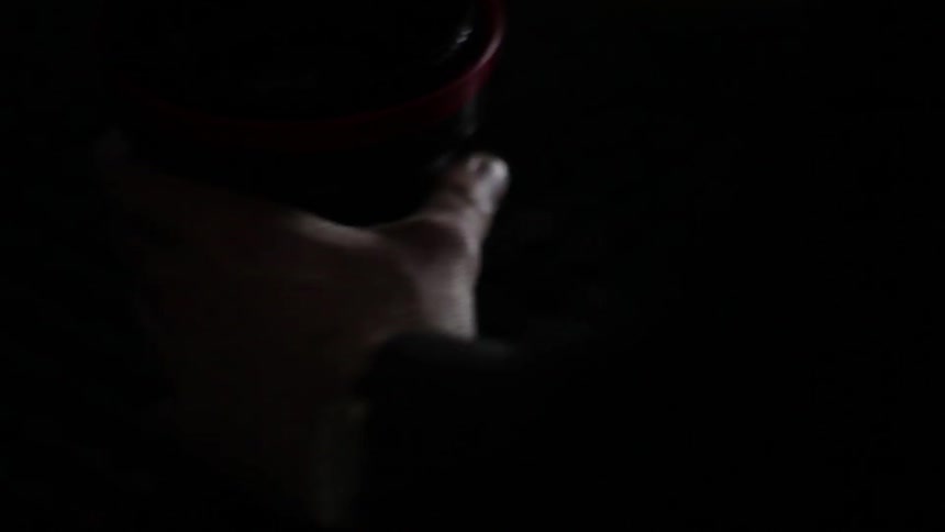 Man using a hose on a machine in a dark room