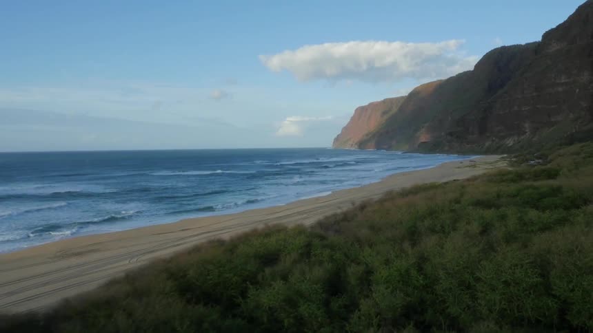 View of a beach with hills on the side and a clear sky