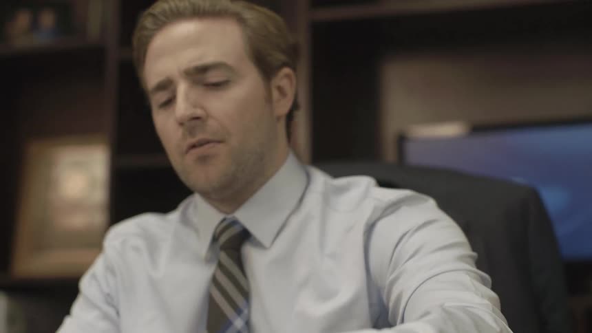 A man sits at a desk and looks through paperwork