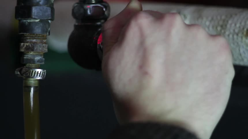 A persons hand turning a valve then liquid coming out of a hose