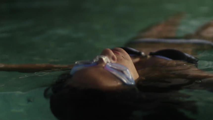 Woman in goggles floats on her back in ocean water