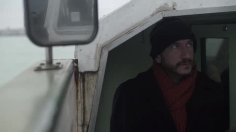 A man stands in the inside of a boat as it travels