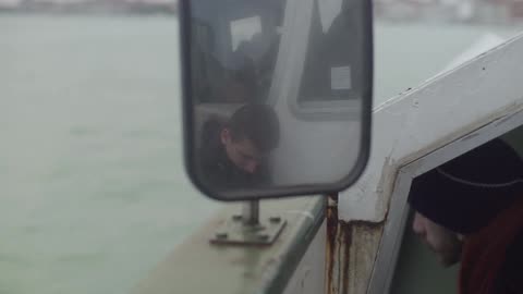 The reflection of a man in a boat mirror