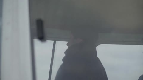 A man in a coat looking out of a window