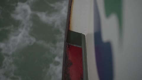 Side of a boat cutting through water as it travels along