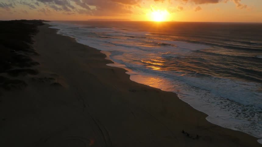 Sun setting as waves crash on a shore