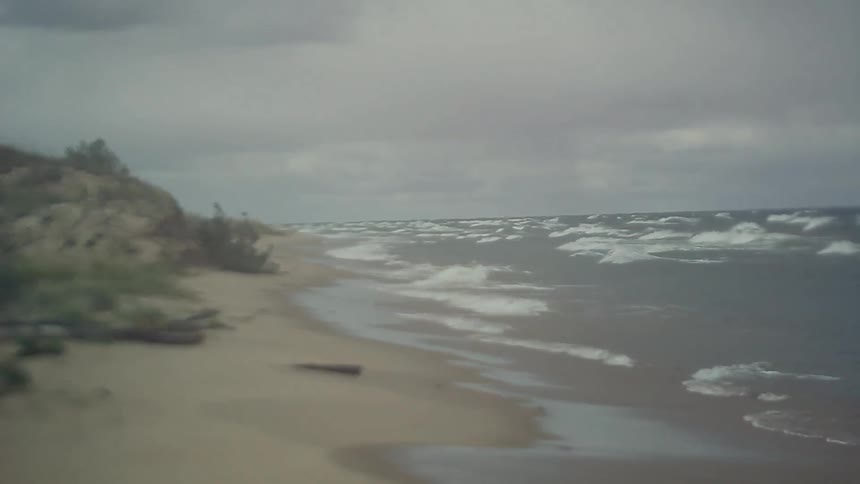 Cloudy beach with waves crashing on the shore