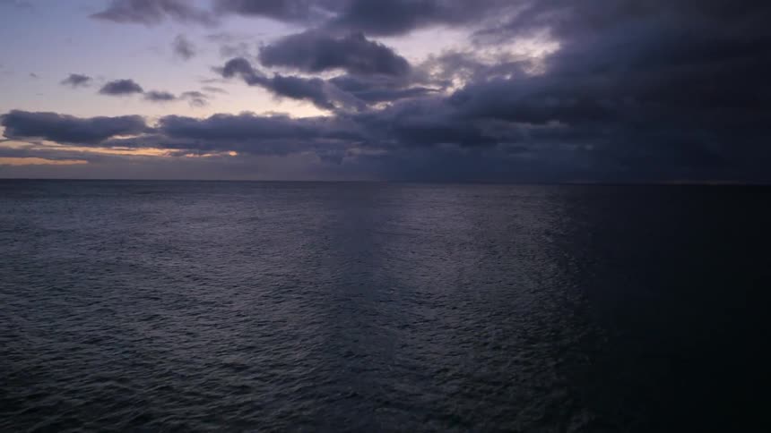 Waves rolling onshore under a cloudy sky at sunset
