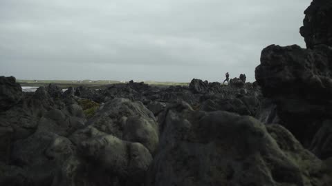 A person performs yoga on a rocky beach on a cloudy day