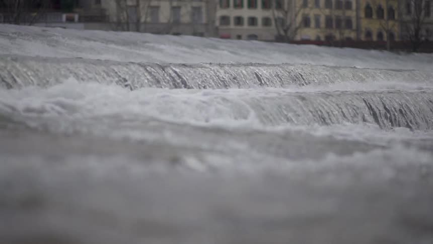 Fast moving waters with buildings in the background
