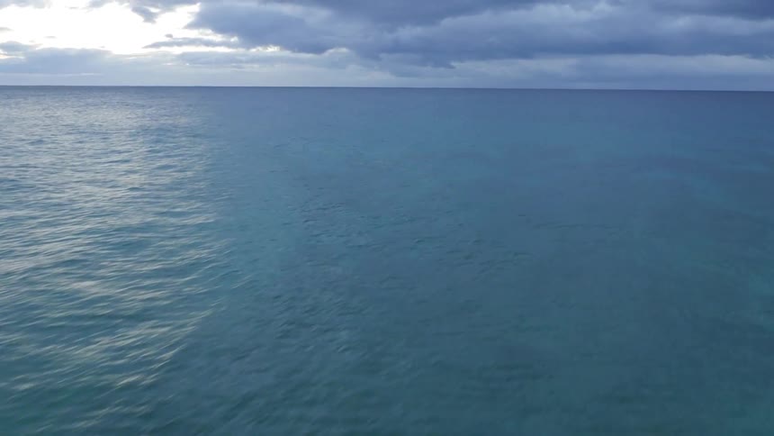 Fast moving pan over a beach into the ocean on a cloudy day